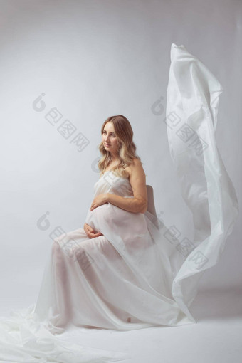 优雅的怀孕了年轻的女人站穿飞行白色织物怀孕<strong>孕妇母亲</strong>概念