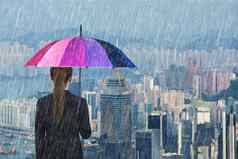业务女人持有五彩缤纷的伞下降雨城市