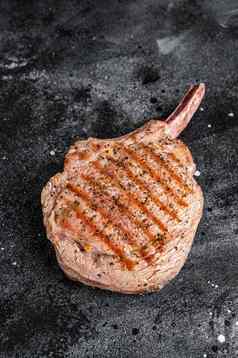 烧烤烤战斧牛肉小牛肉牛排屠夫表格黑色的背景前视图