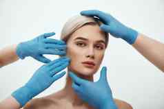 面部手术美丽的金发女郎女人等待面部手术外科医生蓝色的医疗手套检查脸