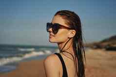 快乐的女人黑色的泳衣太阳镜海滩走旅行
