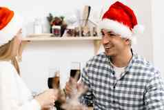 年轻的夫妇圣诞老人帽子喝酒庆祝圣诞节