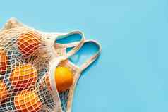 网白色棉花可重用的袋橙子蓝色的背景环境友好的购物环境概念健康的食物柑橘类水果维生素的地方文本