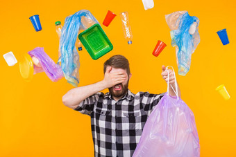 环境污染塑料回收问题生态问题概念伤心男人。持有垃圾袋覆盖眼睛棕榈黄色的背景