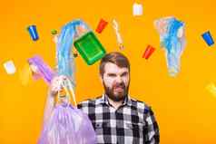 环境污染塑料回收问题生态问题概念不高兴男人。持有垃圾袋黄色的背景