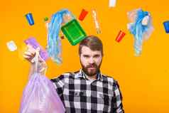 世界环境一天塑料回收问题环境灾难概念愤怒的男人。持有垃圾袋回收显示拇指黄色的背景