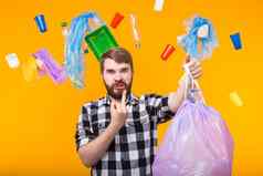 塑料回收问题生态环境灾难概念愤怒的男人。持有垃圾袋黄色的背景