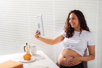 快乐怀孕了年轻的美丽的女人会说话的妈妈视频调用早....早餐概念沟通积极的的态度怀孕