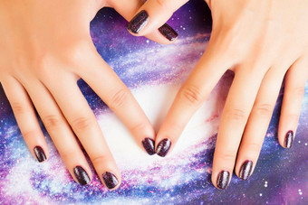 修指甲时尚的概念女人手指指甲紫色的闪闪发光的指甲宇宙宇宙背景