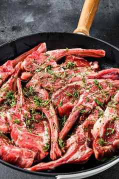生新鲜的羊肉肋骨排腌制百里香薄荷锅黑色的背景前视图