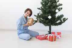 年轻的女人打开礼物圣诞节树圣诞节一年概念