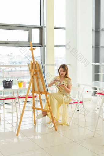 艺术类画创造力概念女学生坐着前面画架调色板画笔