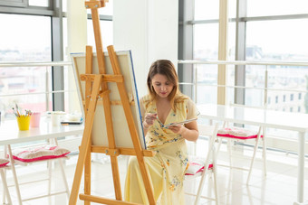 <strong>艺术类</strong>画创造力概念女学生坐着前面画架调色板画笔
