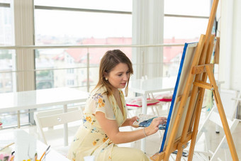 <strong>艺术类</strong>画创造力概念女学生坐着前面画架调色板画笔