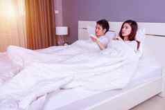 年轻的夫妇说谎床上远程控制空气护发素卧室