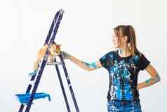 年轻的女人画家设计师工人油漆墙猫坐在梯工作