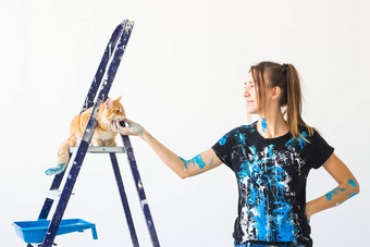 年轻的女人画家抚摸猫设计师工人油漆墙宠物坐在梯工作