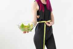 年轻的身份不明的女人运动员紫色的头发措施腰测量磁带持有蔬菜沙拉概念适当的营养好形状
