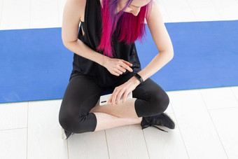 年轻的苗条的身份不明的女人紫色的头发脉冲燃烧<strong>卡</strong>路里聪明的看智能手机坐着体育垫<strong>健身房</strong>概念应用程序体育