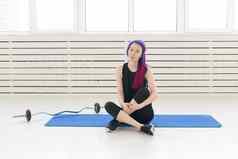 年轻的混合比赛女孩赶时髦的人紫色的头发坐着体育运动席杠铃健身球健身房概念常规的锻炼健身