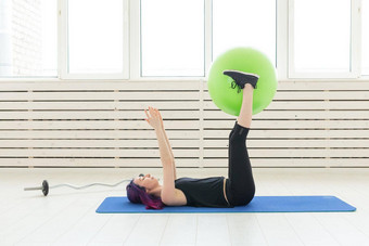 年轻的苗条的女孩锻炼伸展运动绿色健身球明亮的健身房健康的回来<strong>韧带</strong>概念