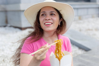 年轻的积极的女孩他吃中国人面条木筷子外卖午餐概念高热量的健康的食物