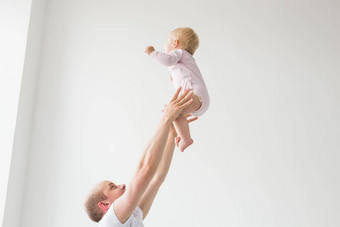 快乐年轻的父亲提升可爱的婴儿高空气支出享受时间女儿