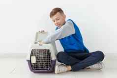 笑积极的男孩持有笼子里苏格兰褶皱猫坐着地板上公寓宠物保护概念