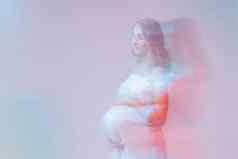 优雅的怀孕了年轻的女人站穿光织物怀孕幻想仙女演讲概念复制空间