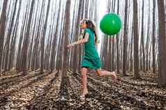 美丽的金发女郎女孩穿着绿色跳森林气球