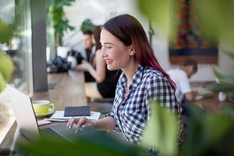 一边视图年轻的女商人坐着表格咖啡商店表格杯咖啡移动PC背景白色墙窗口