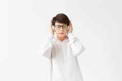 漂亮的敏锐的中年女人眼镜白色毛衣听最喜欢的音乐耳机白色背景在线广播音乐订阅概念