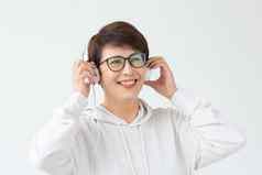 漂亮的敏锐的中年女人眼镜白色毛衣听最喜欢的音乐耳机白色背景在线广播音乐订阅概念