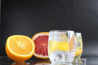 烹饪柠檬水水玻璃冰水果橙色葡萄柚黑色的背景夏天饮料柠檬水喝