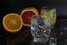 溅水玻璃水冰附近的水果橙色葡萄柚冰黑色的背景让人耳目一新冷冰喝