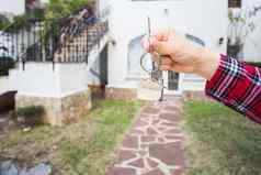 真正的房地产财产概念手持有房子键房子形状的钥匙链前面首页