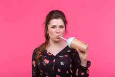 食物喝人概念年轻的女人喝鸡尾酒奶昔粉红色的背景