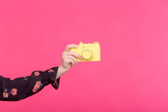 拍摄古董概念女手黄色的复古的相机粉红色的背景复制空间