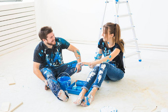改造重新装饰内饰概念年轻的夫妇坐着白色地板上对于油漆有趣的