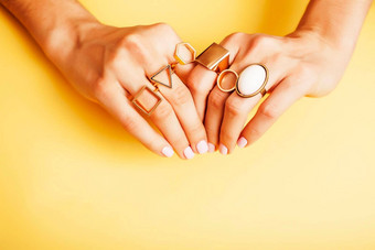 女人手修指甲珠宝环黄色的背景美风格概念