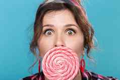 糖果饮食垃圾食物概念肖像惊讶美女女人大棒棒糖蓝色的背景