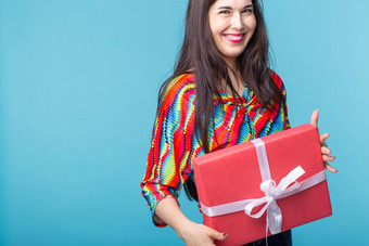 快乐的好年轻的浅黑肤色的女人女人持有红色的礼物盒子手蓝色的背景复制空间概念假期礼物