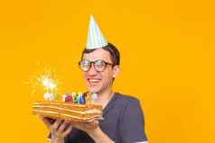 疯狂的快乐的亚洲的家伙眼镜持有燃烧蜡烛手祝贺的自制的蛋糕黄色的背景复制空间生日周年纪念日庆祝活动