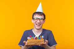 积极的有趣的年轻的亚洲的家伙帽燃烧蜡烛自制的蛋糕手摆姿势黄色的背景周年纪念日生日概念