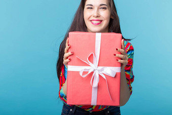 快乐的好年轻的浅黑肤色的女人女人持有红色的礼物盒子手蓝色的背景概念假期礼物