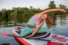 年轻的美丽的女人冥想海paddleboarding健康的生活方式