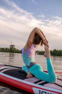 年轻的美丽的女人冥想海paddleboarding健康的生活方式