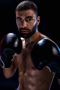 强大的肌肉发达的拳击手黑色的拳击手套男人。拳击站黑色的背景