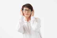 漂亮的敏锐的中年女人眼镜白色毛衣听最喜欢的音乐耳机白色背景复制空间在线广播音乐订阅概念