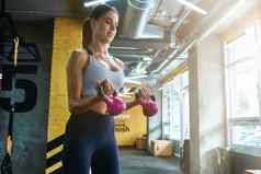 年轻的健身女人运动服装锻炼哑铃工业健身房培训肱二头肌